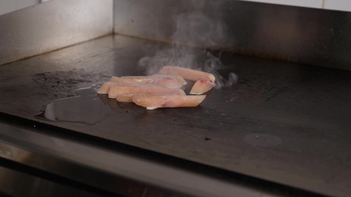 厨师的特写镜头是把鸡肉放在炉子上，盖上盖子。
