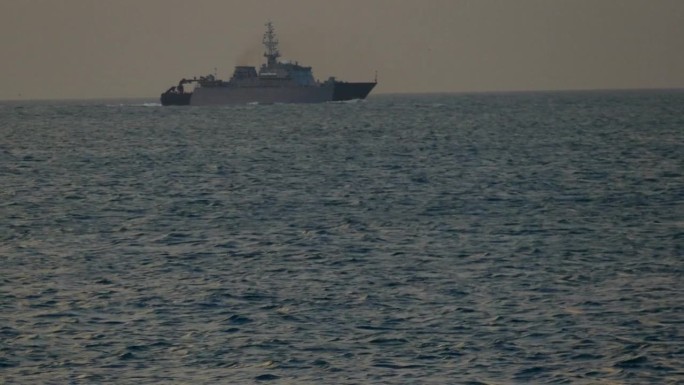 一艘军舰的剪影在黄昏的海面上