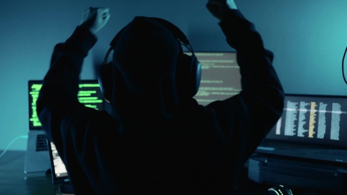 专业黑客成功使用密码登录侵入公司数据服务器，并在黑暗的气氛中举手庆祝。网络犯罪，数字系统安全