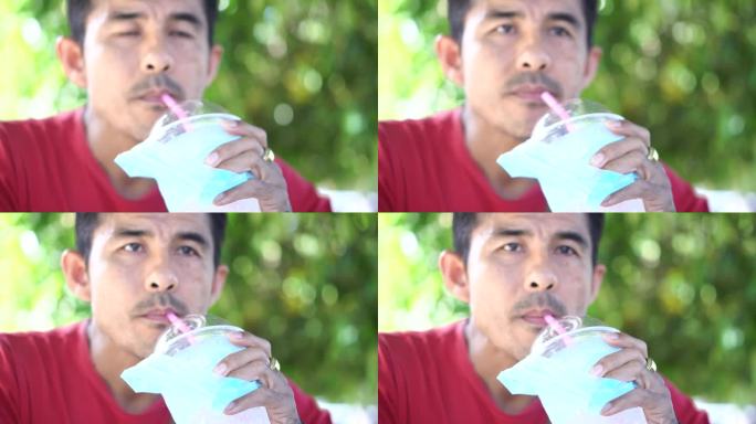 一个男人用一根吸管从杯子里喝水。