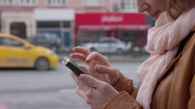 土耳其伊斯坦布尔城市街道上女游客用智能手机的手持侧视图