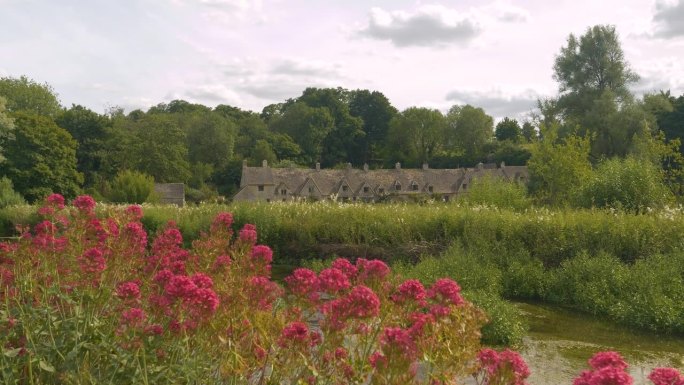穿过平静的河流，眺望着著名的Bibury村田园诗般的石头房子