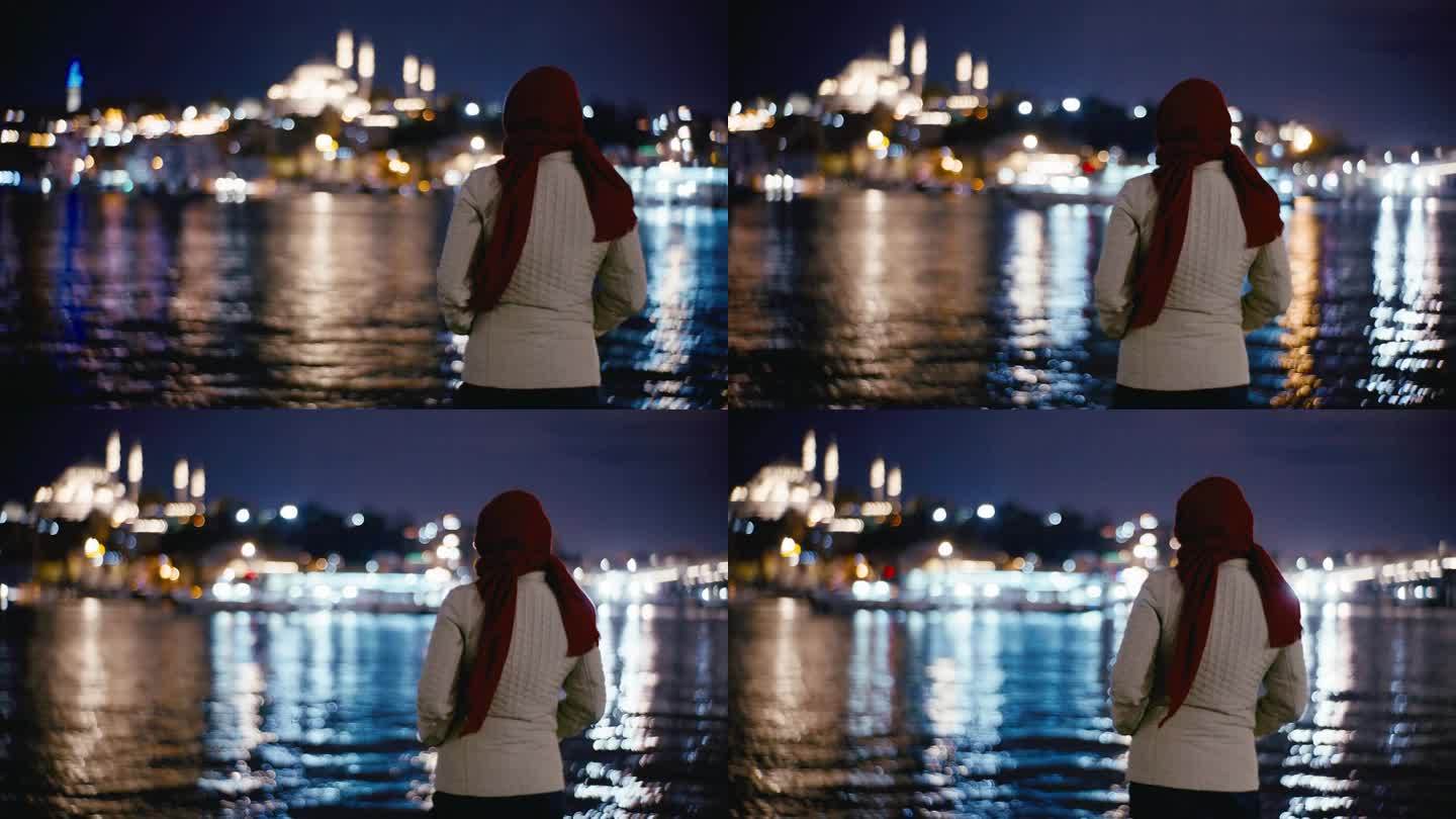 一名女子欣赏着城市灯光反射在博斯普鲁斯海峡上的大桥夜景