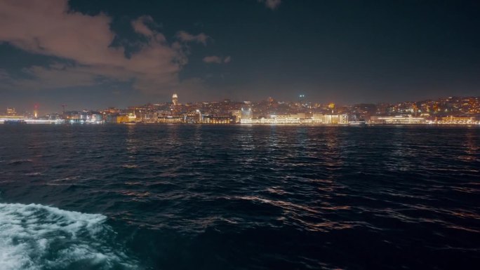 船的视角照亮城市景观的马尔马拉海对天空在夜间伊斯坦布尔，土耳其