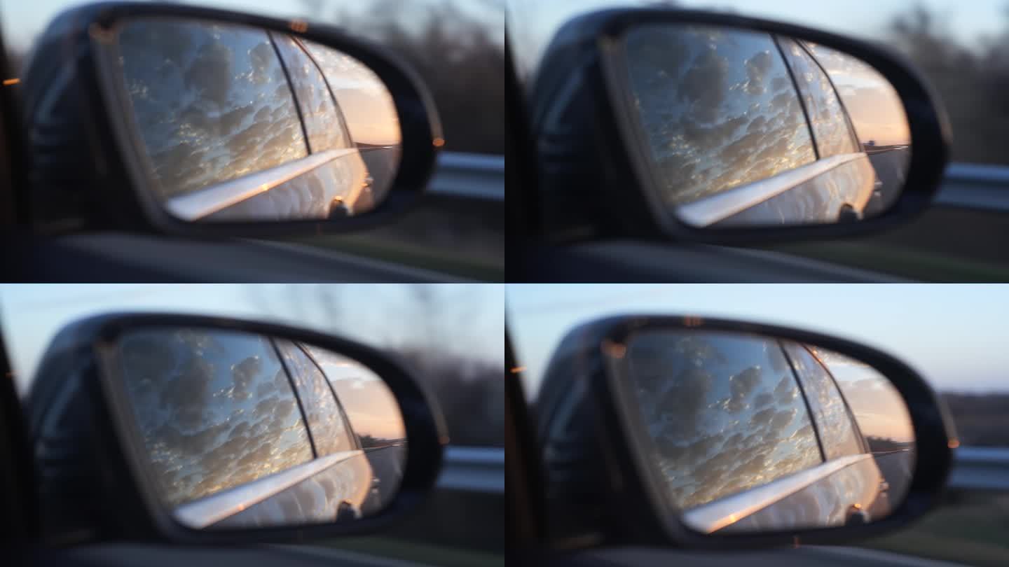 晚霞映照在行驶中的汽车后视镜上。近距离拍摄，实时拍摄，没有人