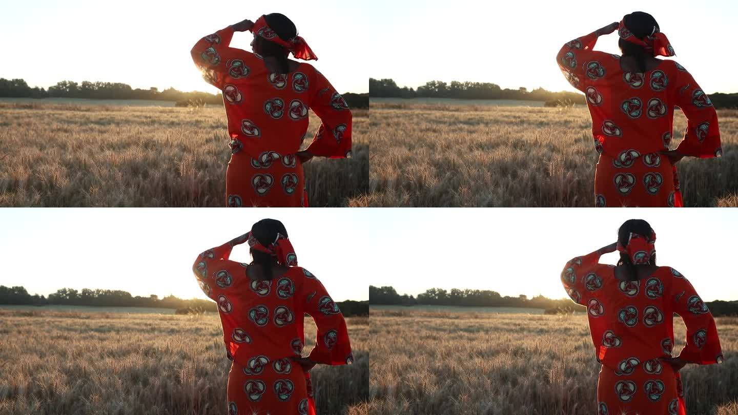 日落或日出时，身穿传统服装的非洲女农民站在麦田里，种着小麦或大麦