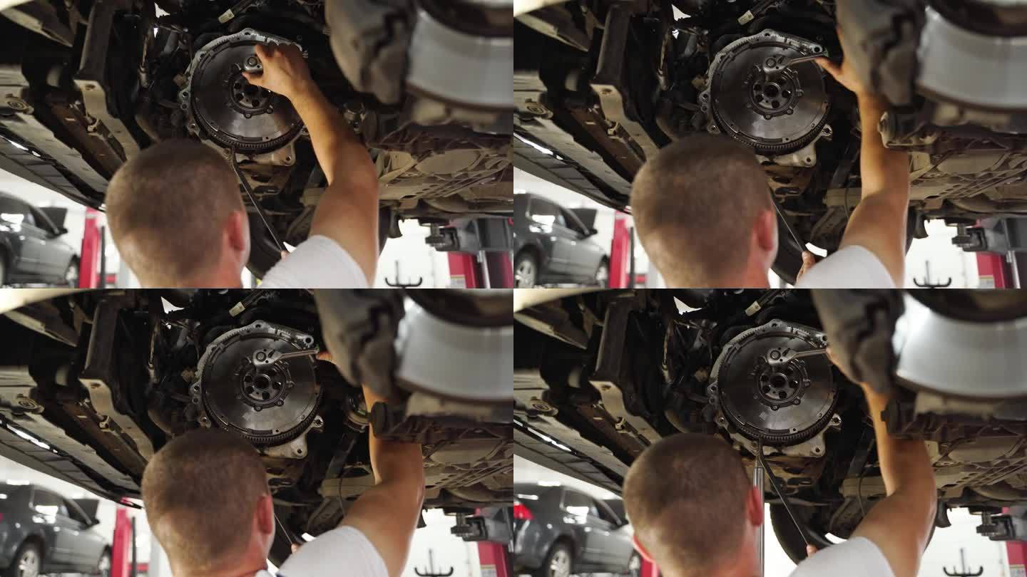 汽车修理工在车上安装离合器片。修理工在车辆变速箱上工作，更换分离轴承，调整离合器片。车间技术员在升降