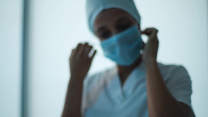 疲惫不堪的年轻非洲女医生或护士的特写肖像，戴着统一的医疗帽，在做完手术后摘下口罩