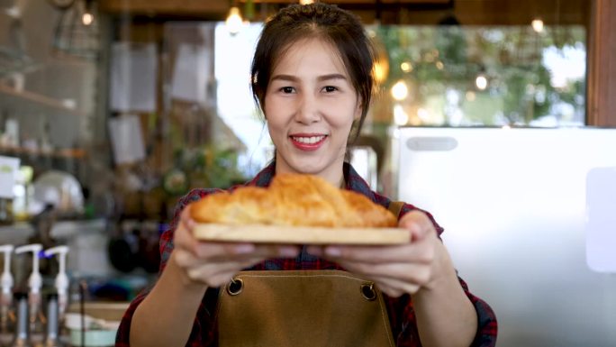 4k，生活方式快乐的面包店老板提供美味的羊角面包盘，亚洲女性站在镜头前，小企业创业聘请有吸引力的模特