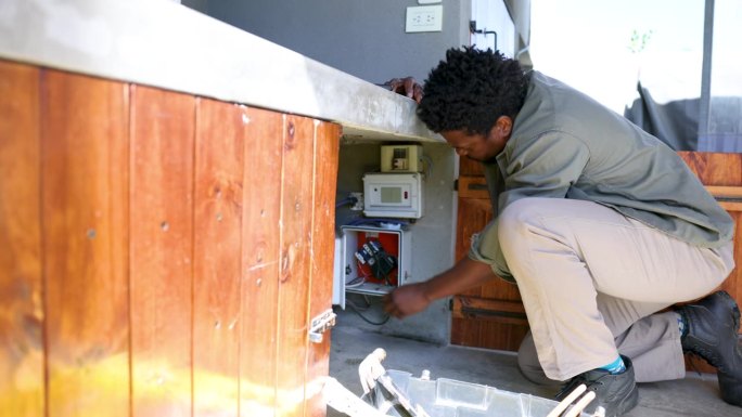 非裔美国电工在检查房子的保险丝盒