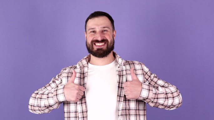 快乐的大胡子男人，大拇指和良好的工作在赢得，成功或感谢你对一个紫色的工作室背景。
