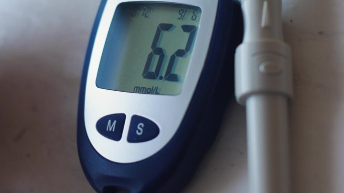 测量血糖的装置，便携式血糖仪。血糖仪屏幕上的血糖读数。糖尿病保健