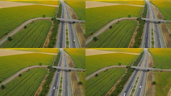 4K鸟瞰图，绿色农田之间的城际道路与快速行驶的汽车。无人机对高速公路交通的俯视图。