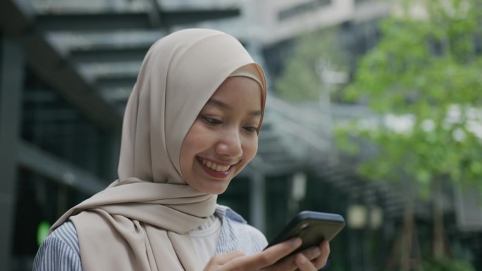 在网上搜索的女性穆斯林肖像。戴头巾的年轻女子微笑着