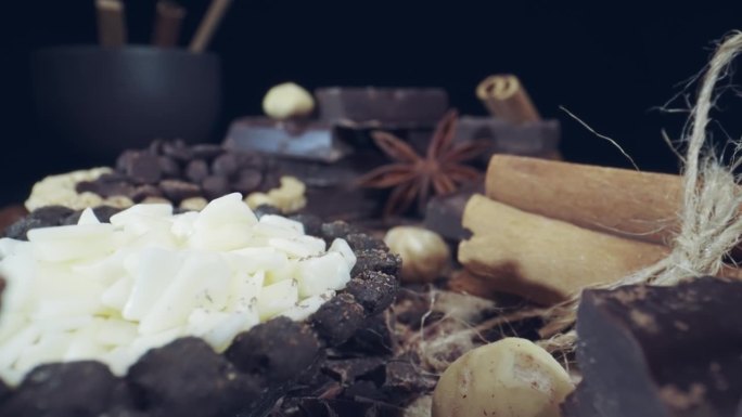 宏观舒适的场景，各种巧克力与肉桂棒，巧克力块在木桌上，榛子和干八角星