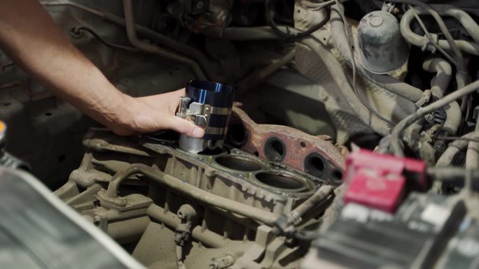 汽车修理工使用环形压缩机将活塞安装到发动机缸体中。专业维修人员重新组装电机，确保车辆性能。亲历汽车维