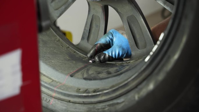 汽车修理工在车库里用车轮平衡器平衡汽车轮胎。精密对中，旋转测试，平衡检查，确保安全驾驶。车辆保养，轮
