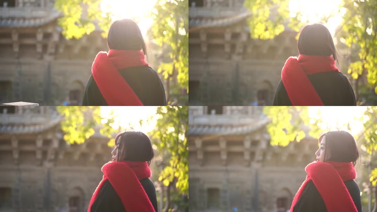 一个戴红色围巾的女人站在阳光下看远方背影
