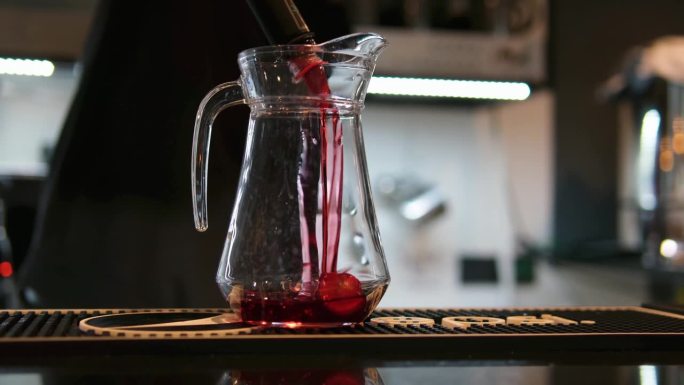 咖啡师用手将草莓糖浆、柠檬水和浓缩咖啡倒入一个装有冰块的杯子里。特写镜头