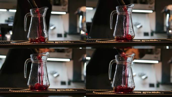 咖啡师用手将草莓糖浆、柠檬水和浓缩咖啡倒入一个装有冰块的杯子里。特写镜头