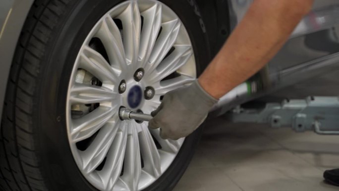 汽车修理工用扭矩扳手固定高级车辆的轮胎。在高端汽车服务中，专家确保车轮对中、安全。专业工作，轮胎安装