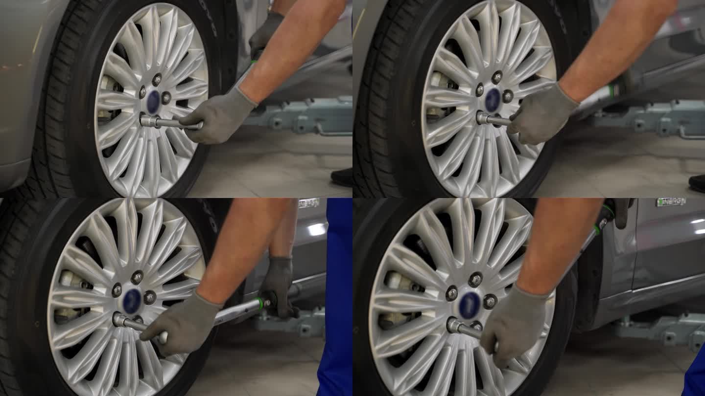 汽车修理工用扭矩扳手固定高级车辆的轮胎。在高端汽车服务中，专家确保车轮对中、安全。专业工作，轮胎安装