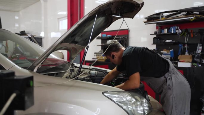 汽车修理工为汽车的燃气系统安装LPG减速机。专业执行替代燃料转换，在发动机舱安装汽化器，优化多点喷射