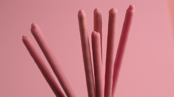 粉红色糖釉中的脆棒在粉红色的背景上旋转。