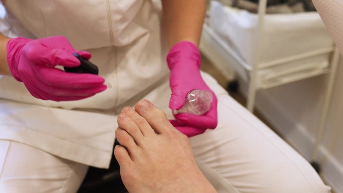 在水疗沙龙用清漆涂指甲的女人的腿。腿部和指甲皮肤护理。足疗程序和SPA过程。特写，选择性对焦。