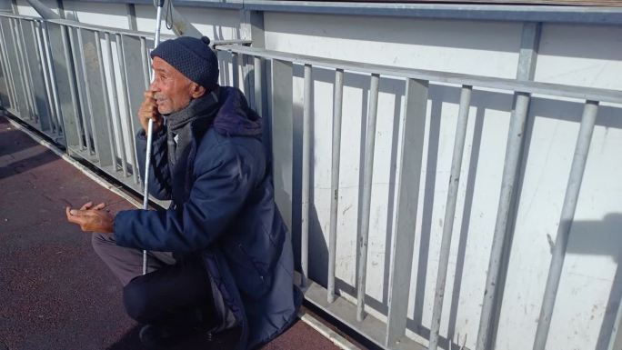 无家可归的老人坐在街上乞讨