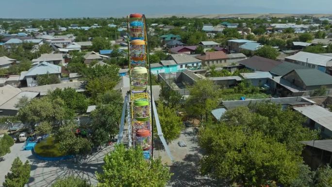 在哈萨克斯坦奇姆肯特附近的Sayram废弃主题公园，彩色的生锈摩天轮。航空轨道拍摄
