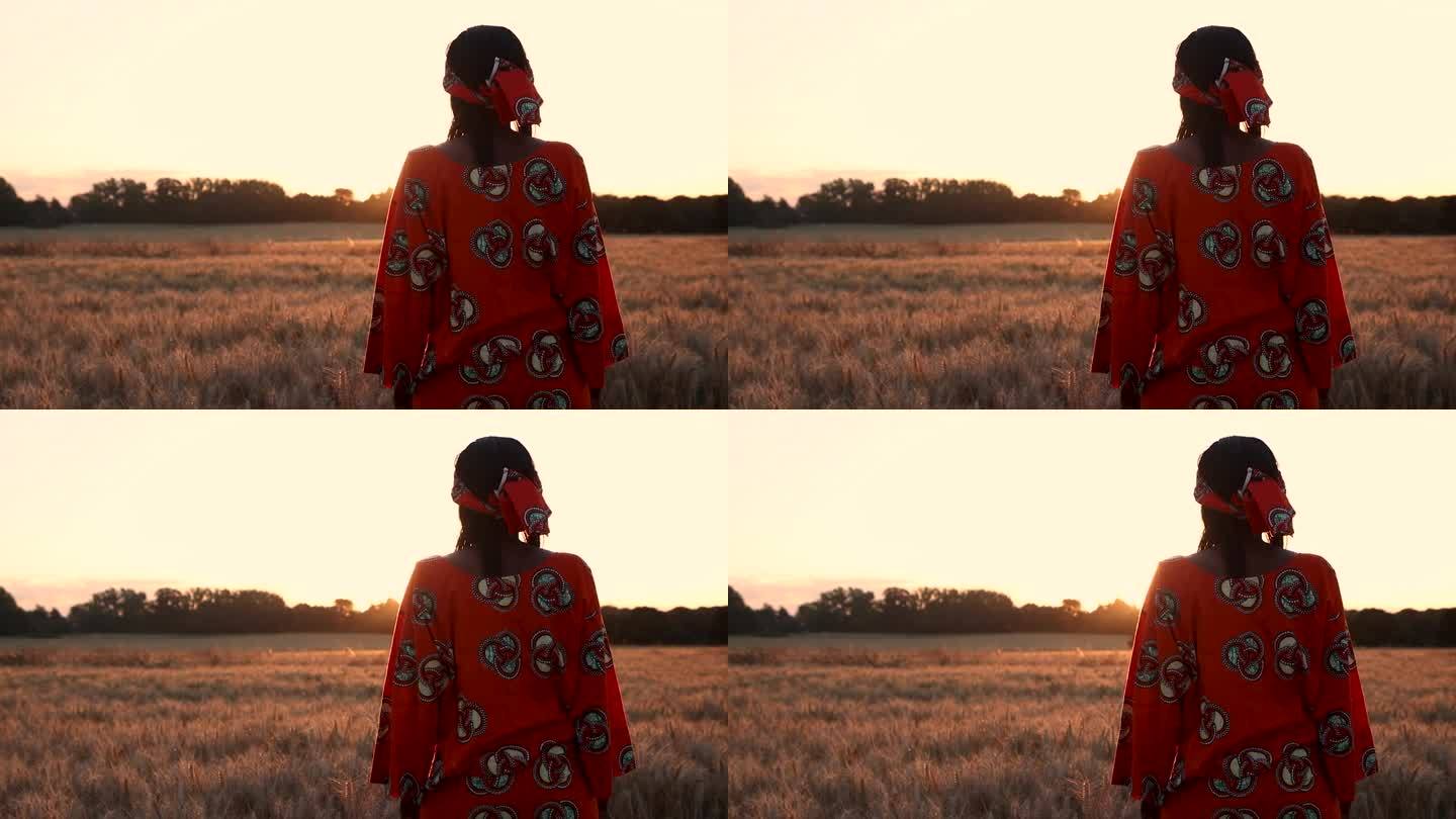 日落或日出时，身穿传统服装的非洲女农民站在麦田里，种着小麦或大麦