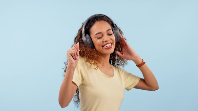 耳机，跳舞和年轻女子在录音室里听音乐，收音机或播放列表的乐趣。快乐，微笑和年轻的女性人从哥伦比亚流的