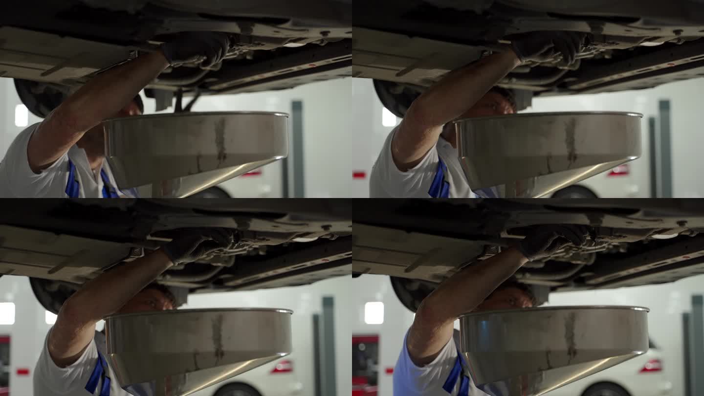 汽车修理工在日常保养时把车里的旧油放掉。专业从事车库更换润滑油，车辆吊装，车间环境。亲自操作换油程序