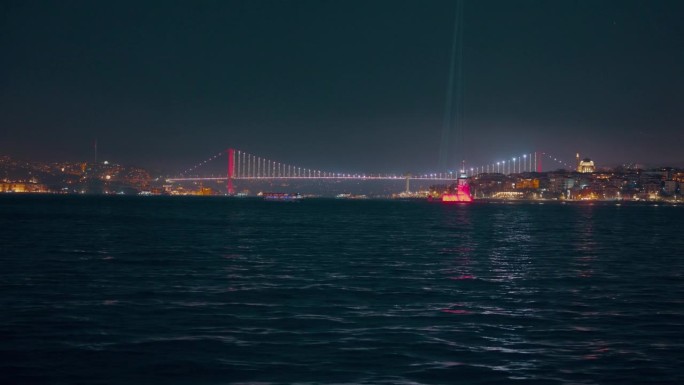 船的视角照亮博斯普鲁斯大桥和城市景观的马尔马拉海对晴朗的天空在夜间伊斯坦布尔，土耳其