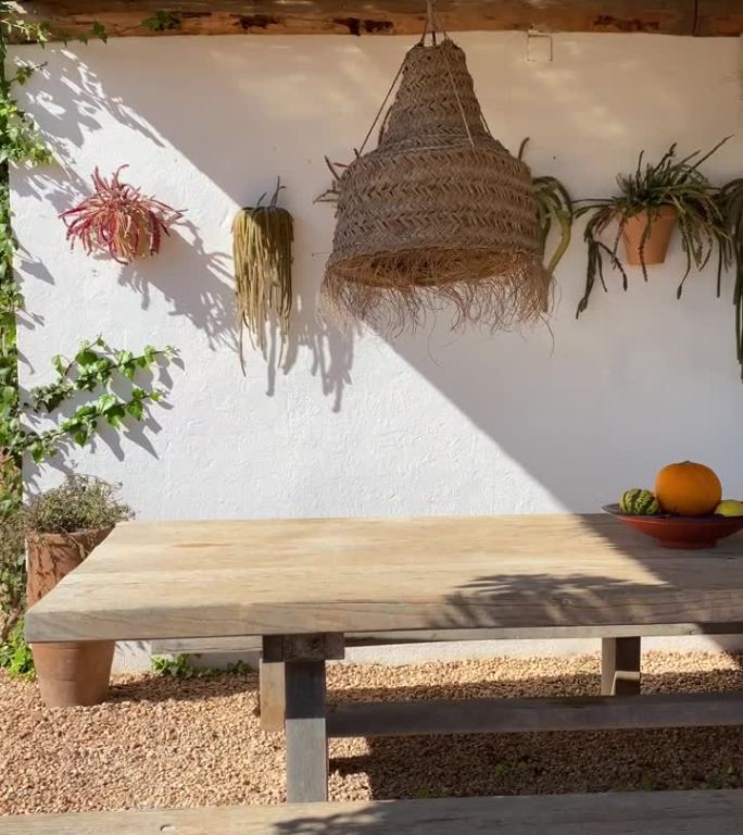 在伊比沙岛的一所房子里，露天区域的野餐桌与干草天花板的垂直拍摄