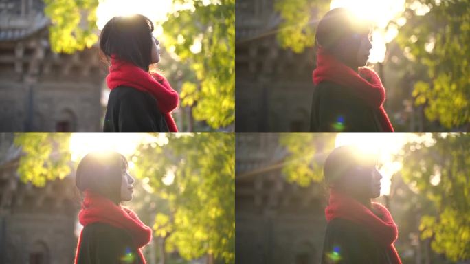 一个戴红色围巾的女人站在阳光下看远方风景