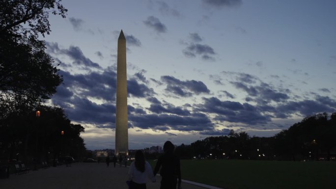 一对夫妇在日落后走向华盛顿纪念碑