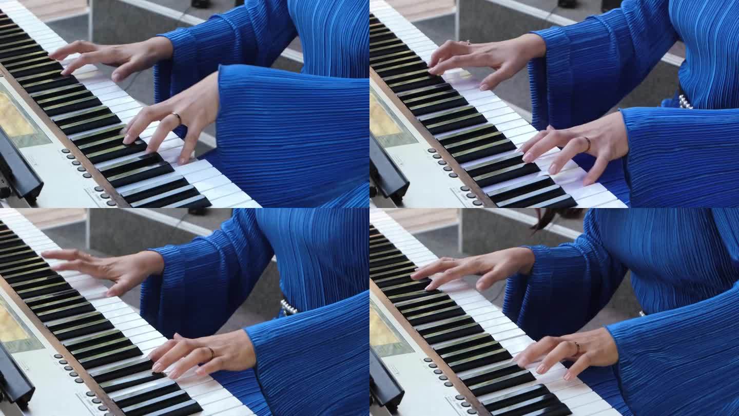 年轻女子在户外弹奏数字钢琴。在城市市场举办小型音乐会。穿着电蓝色连衣裙的女人。