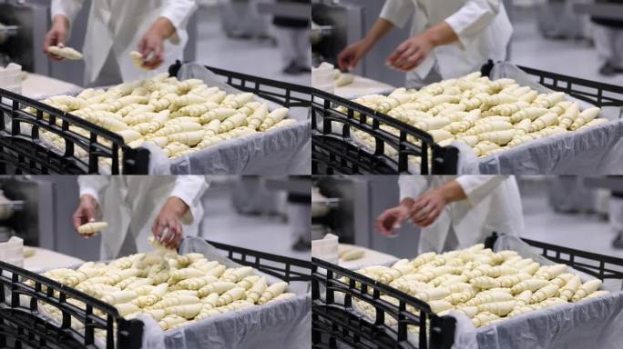 在一家工业面包店的生产线上，无法辨认的女工将牛角面包放在一个篮子里，并将有缺陷的牛角面包放在另一个篮