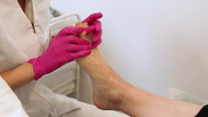 足疗大师在医学面膜按摩脚部。在Spa沙龙接受经典足疗按摩霜程序的女性腿部。腿部和指甲皮肤护理。足疗程