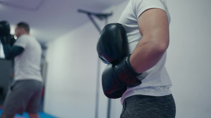 体育俱乐部男子自由搏击运动员戴拳套学习防踢技术的镜头特写