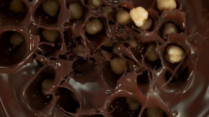 剥皮榛子落入旋转融化巧克力的超级慢动作镜头，1000 fps。