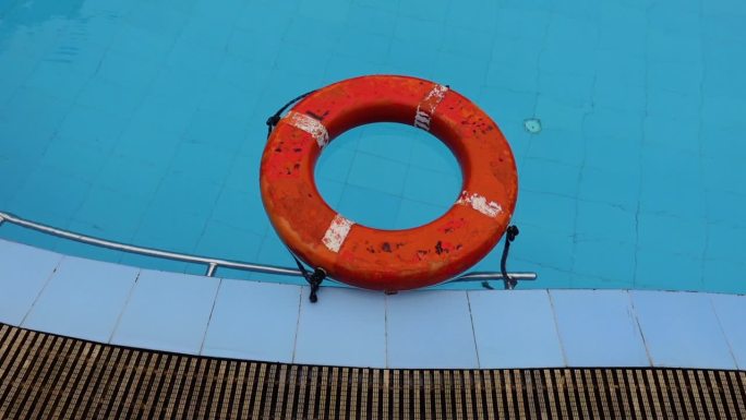 一个旧的救生圈漂浮在游泳池的蓝色水面上。