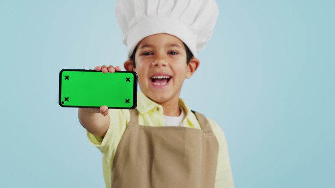 厨师孩子，脸或手机绿屏在工作室的社交媒体，烹饪教程广告或下载。蓝色背景，空间或快乐的孩子与通知在线营