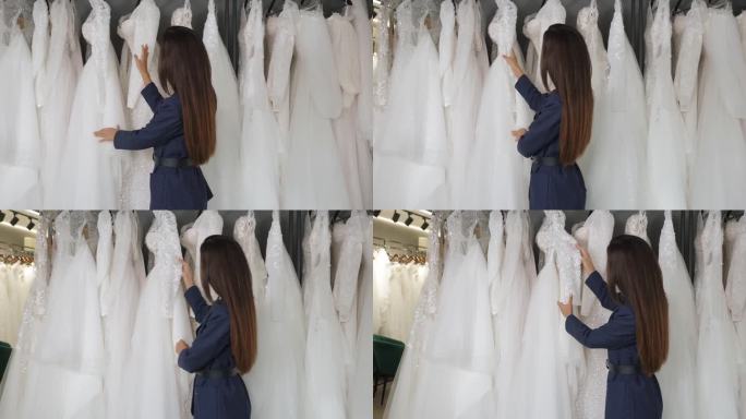 一位年轻美丽的女子在婚礼沙龙里挑选婚纱。