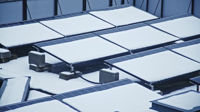 屋顶安装的光伏太阳能电池板阵列覆盖在厚厚的雪层中，阻挡了太阳光，减少了电能的产生