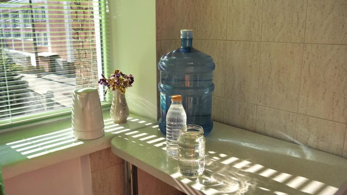 一瓶水放在桌子上，另一瓶水由净水服务人员拿来放在桌子上