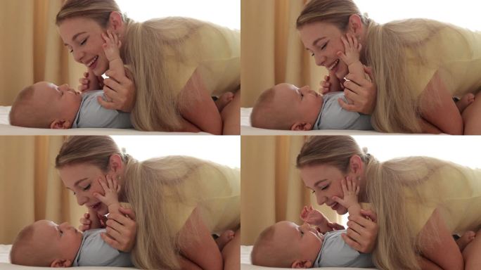 电影的特写镜头，年轻快乐的母亲和她的男婴在卧室里玩耍，在一个早晨醒来。爱的概念，为人父母，童年，生命