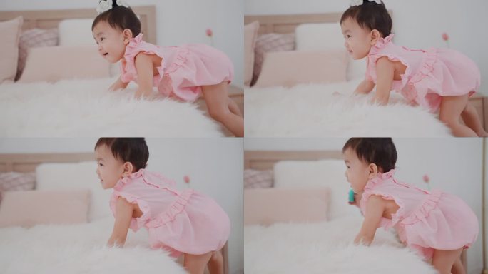 可爱的亚洲女婴穿着可爱的粉色连衣裙，在卧室里爬上床，试图够到床上的东西。